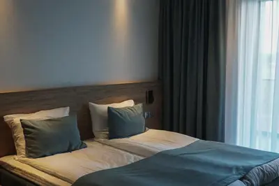 a bed with two pillows sitting next to a window at Molėtai Hotel in Molėtai