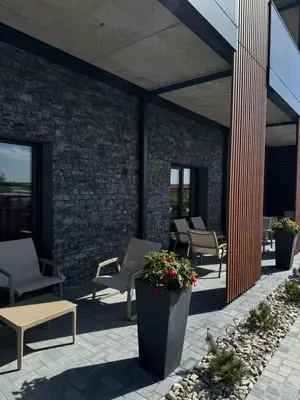 a patio with chairs and tables and a brick wall at Molėtai Hotel in Molėtai