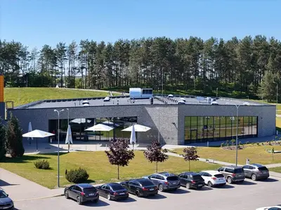 a parking lot with cars parked in front of a building at Molėtai Hotel in Molėtai