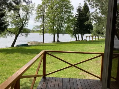 a wooden porch with a view of a lake at Našio kempingas in Antanaše