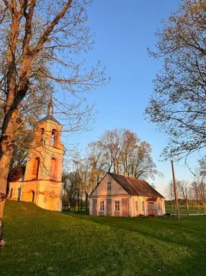 an old church and a house in a field at Red Brick House in Naciūnai