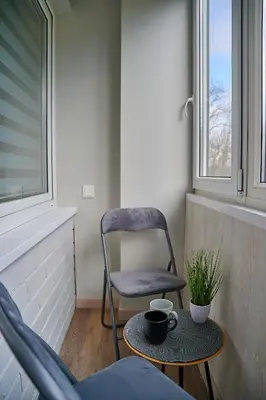 a chair and a table in a room with a chair at COZY VISIT, Studio4 with balcony, 24h Self Chek-in, on the first floor in Kaunas