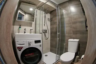 a bathroom with a shower and a washing machine at COZY VISIT, Studio4 with balcony, 24h Self Chek-in, on the first floor in Kaunas