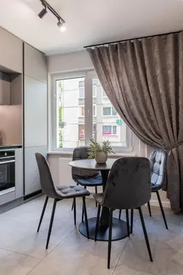 a dining room with a table and chairs and a window at Grey Apartments in Šiauliai