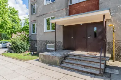 a building with a brown door and stairs in front at Grey Apartments in Šiauliai