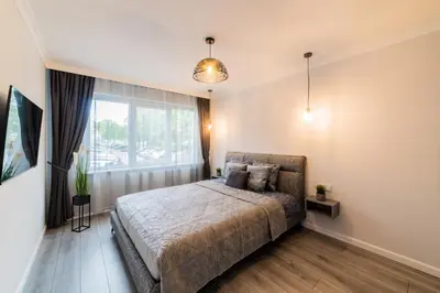 a bedroom with a bed and a window at Grey Apartments in Šiauliai