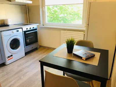 a kitchen with a table and a washing machine at COZY Apartment in the SUN CITY in Šiauliai