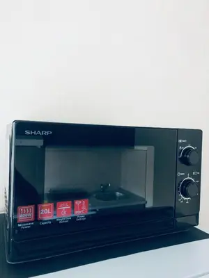 a black microwave sitting on top of a counter at COZY Apartment in the SUN CITY in Šiauliai