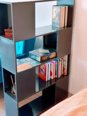 a book shelf filled with books next to a bed at COZY Apartment in the SUN CITY in Šiauliai