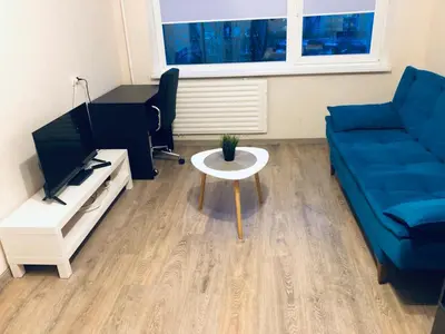 a living room with a blue couch and a table at COZY Apartment in the SUN CITY in Šiauliai