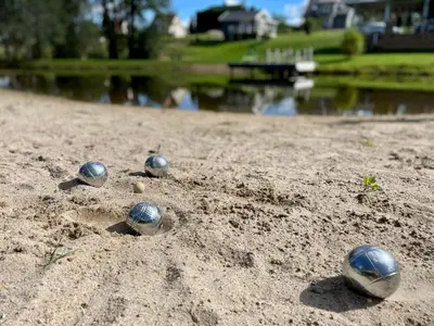 a group of balls in the sand next to a lake at Žalčio guolis in Lekėčiai
