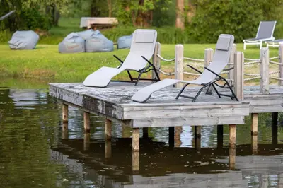 a group of chairs sitting on a dock in the water at Žalčio guolis in Lekėčiai