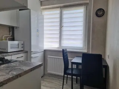 a kitchen with a table and chairs and a window at TILZES 24 APARTMENTS - self check in in Šiauliai