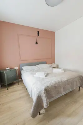 a bedroom with a large bed with a pink wall at Observation Deck Apartments in Kaunas