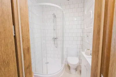 a white bathroom with a shower and a toilet at Observation Deck Apartments in Kaunas