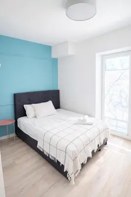 a bedroom with a bed with a white and blue wall at Observation Deck Apartments in Kaunas