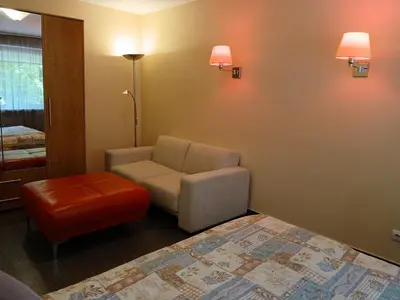 a living room with a chair and a stool at 3 rooms apartment with balcony in Kaunas