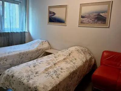 a hotel room with two beds and a red chair at 3 rooms apartment with balcony in Kaunas