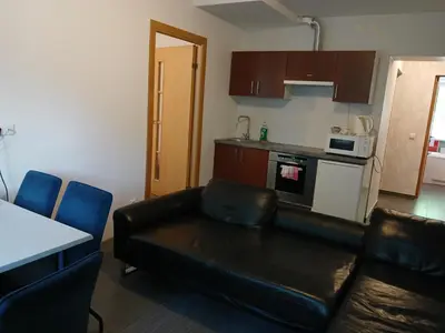 a living room with a black leather couch and a kitchen at 3 rooms apartment with balcony in Kaunas
