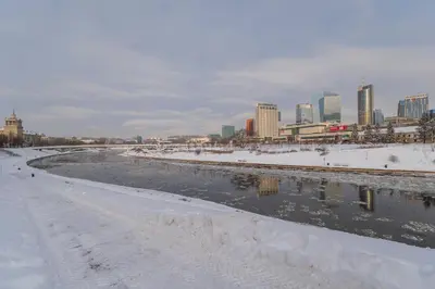 a river covered in snow with a city in the background at Riverside apartment in Vilnius