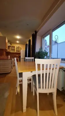 a dining room table with two white chairs and a kitchen at Rehouse, Vilniaus 45 in Vilnius