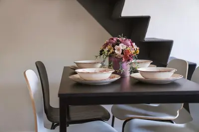 a table with bowls and a vase of flowers at Cozy Loft next to Main Station in Kaunas