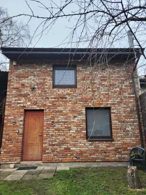 a brick house with a brown door and two windows at Svečių namelis in Kaunas