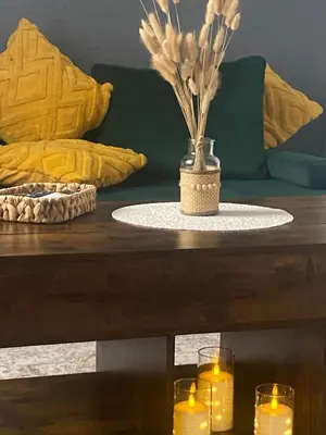 a table with two candles and a vase with flowers at Centro apartments Rokiškis in Rokiškis