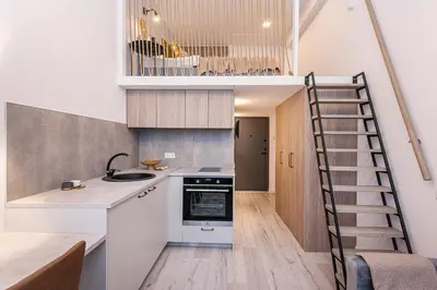 a kitchen with a staircase leading up to a loft at Sigma Skyline Lofts by Reside Baltic in Vilnius