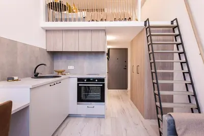 a kitchen with white cabinets and a spiral staircase at Sigma Skyline Lofts by Reside Baltic in Vilnius