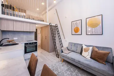 a living room with a couch and a kitchen at Sigma Skyline Lofts by Reside Baltic in Vilnius