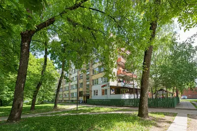 a building in the middle of a park with trees at Partizanų studio apartment #1 by Polo Apartments in Kaunas