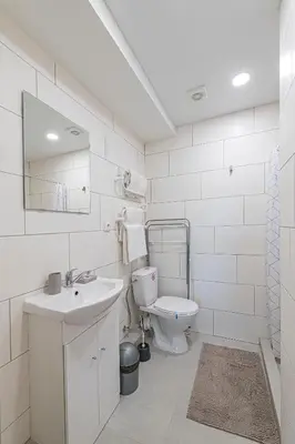 a white bathroom with a toilet and a sink at Partizanų studio apartment #1 by Polo Apartments in Kaunas