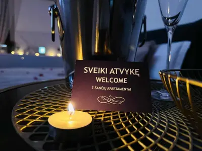 a candle sitting on a table with a wine glass at Ž Šančių- Apartamentai in Kaunas