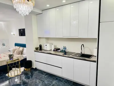 a kitchen with white cabinets and a sink and a bed at Ž Šančių- Apartamentai in Kaunas