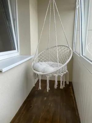 a white swing hanging from a wall in a room at Liepų Apartamentai in Molėtai