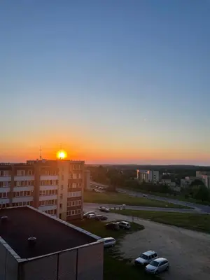 a sunset over a parking lot with cars parked at Liepų Apartamentai in Molėtai