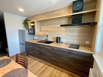 a kitchen with a counter and a clock on the wall at Liepų Apartamentai in Molėtai