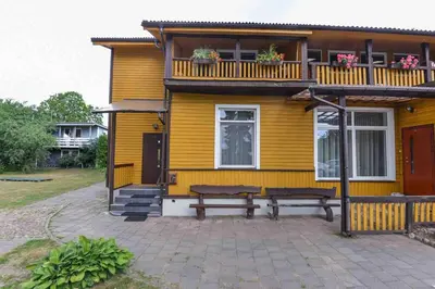 a yellow house with two benches in front of it at Central Family Apt 70 m2 with free Parking & Private Entrance in Druskininkai