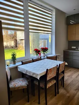 a kitchen with a table and chairs and windows at Central Family Apt 70 m2 with free Parking & Private Entrance in Druskininkai