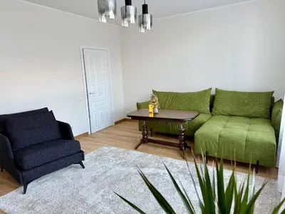a living room with a green couch and a chair at Central Family Apt 70 m2 with free Parking & Private Entrance in Druskininkai