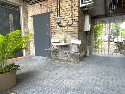 a patio with a table and chairs next to a brick wall at Green Bridge Studio in Vilnius