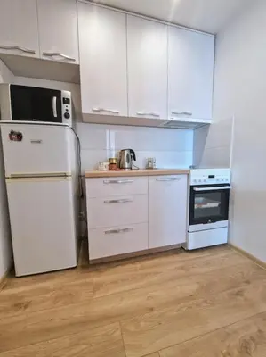 a kitchen with white cabinets and a white refrigerator at Butas šalia parko in Radviliškis