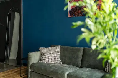 a green couch in a living room with a blue wall at Paupys lofts in Vilnius