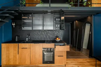 a kitchen with wooden cabinets and a blue wall at Paupys lofts in Vilnius