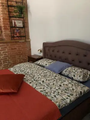 a bed in a bedroom with a brick wall at Boutique Studija Žibutė in Panevėžys