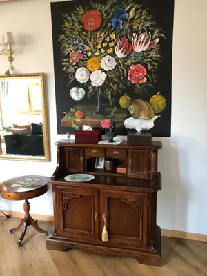 a wooden cabinet with a painting of flowers on the wall at Boutique Studija Žibutė in Panevėžys