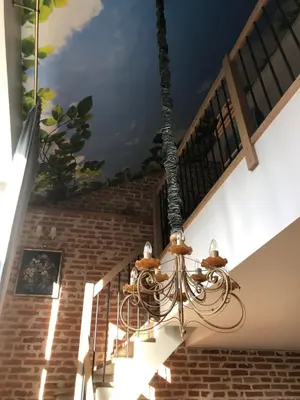 a chandelier hanging from a ceiling with a mural at Boutique Studija Žibutė in Panevėžys
