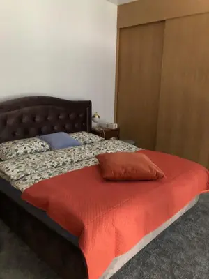 a bed with a red pillow on top of it at Boutique Studija Žibutė in Panevėžys