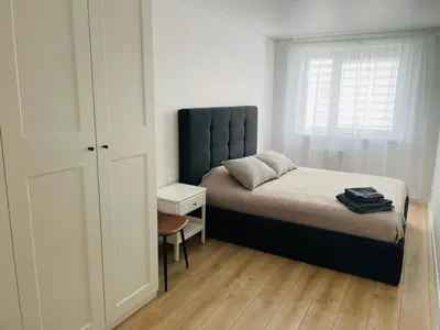 a bedroom with a bed and a chair and a window at LilHouse Apartment in Siauliai Center in Šiauliai